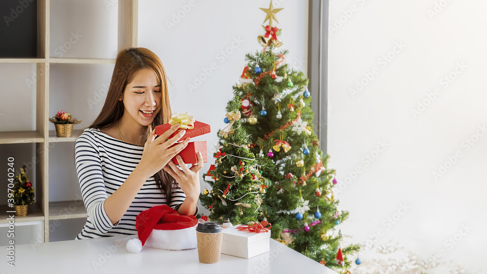 Happy Asian woman holding and opening a beautiful gift box on white table. Happy Christmas and Happy New Year. Happy Asian woman holding and opening a beautiful gift box on white table. Happy Christmas and Happy New Year.
