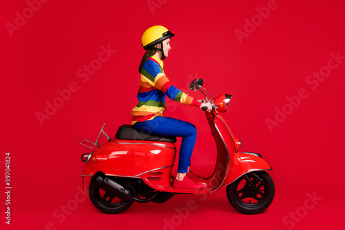 Photo portrait side view of woman riding scooter isolated on vivid red colored background