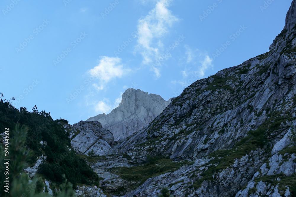 A steep mountain wall on the way to Grimming in Austrian Alps. Dangerous climbing only for professionals. The sky above it is blue, one small cloud. Extreme sport. red path mark on the side.