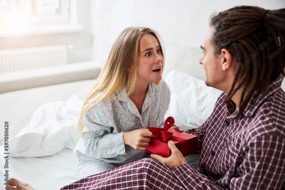 Loving young man giving present to his charming girlfriend Loving young man giving present to his charming girlfriend