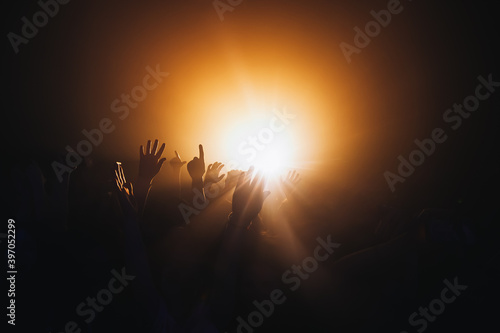 The hands of several fans raised in the air to show support for their favorite band at the concert. The beams of spotlights illuminating the crowd create an atmosphere of energy and excitement.