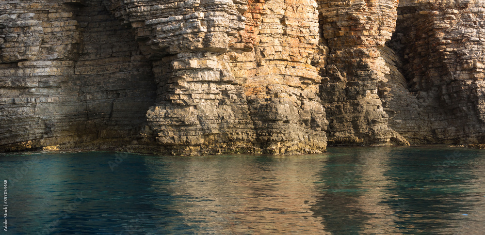 Close up Sea cliff, Layered rocks and stones with turquoise blue sea water