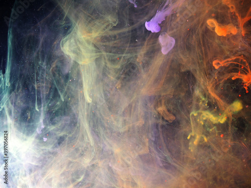 Dissolving paint drops of different colors in water. Red, blue, green, black, purple paint stains in the water.