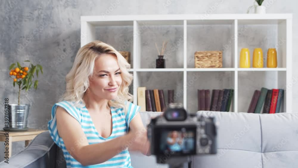Young and attractive woman is recording video blog with a camera. Girl is sitting at home and vlogging. Young and attractive woman is recording video blog with a camera. Girl is sitting at home and vlogging.