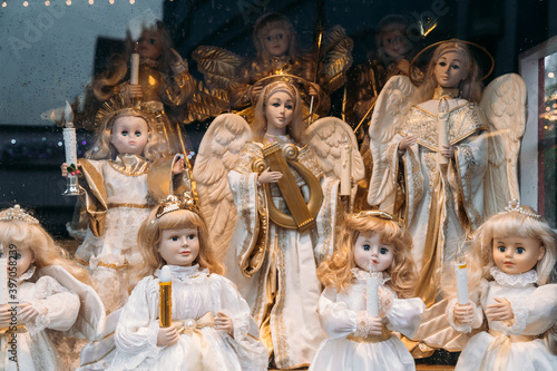Figures of porcelain dolls of angels with candles in the window at Christmas