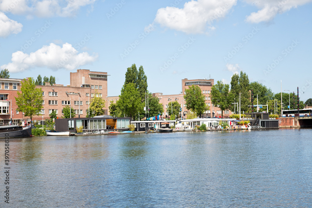 Summery panoramic view of the Amstel river in the South of Amsterdam. Modern highrise MessageBird and houseboats.