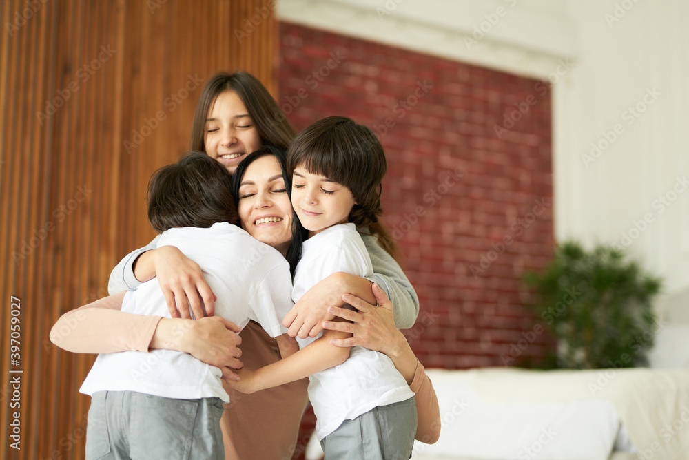 Lovely latin children, teenage girl and two little twin boys hugging their mom while having fun together indoors. Mother playing with her kids at home Lovely latin children, teenage girl and two little twin boys hugging their mom while having fun together indoors. Mother playing with her kids at home