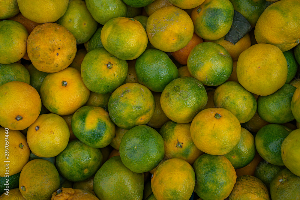 yellow and green tangerines lie in a box