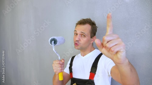 cheerful man with rollers for painting the walls dancing, smiling, looking at camera