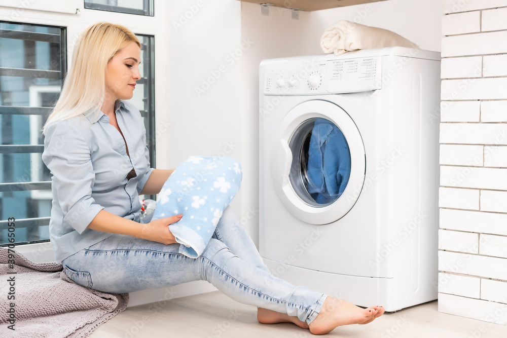 A young housewife with washing machine and clothes. Washing day. A young housewife with washing machine and clothes. Washing day.