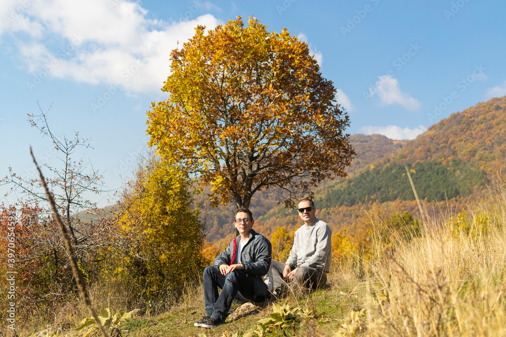 Young men taking a break after long walking in autumn nature Young men taking a break after long walking in autumn nature