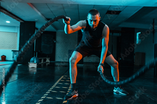 Young man workout with battle ropes. 