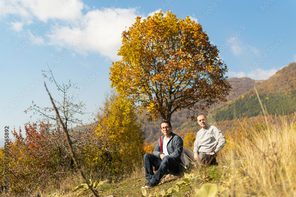 Young men taking a break after long walking in autumn nature Young men taking a break after long walking in autumn nature