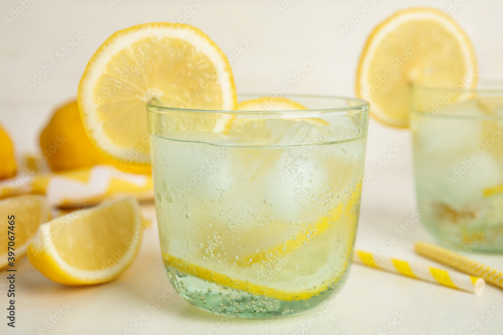 Soda water with lemon slices and ice cubes on white table Soda water with lemon slices and ice cubes on white table