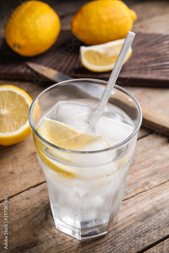 Soda water with lemon slices and ice cubes on wooden table