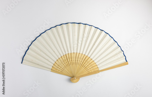 Vintage style white color bamboo folding fan with blue striped at the rim edge isolated in white background.