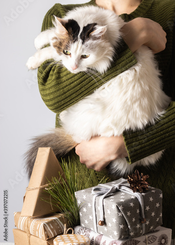 Gifts for Christmas. The girl is holding a white cat in her hands. The concept of the new year and sustainable attitude to life. Zero waste gifts. Hedonism