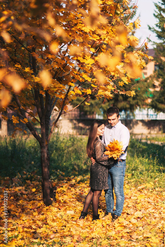 A loving couple in an autumn park on a background of maple leaves