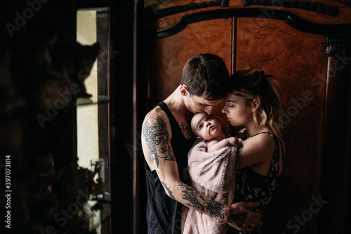 parents with tattoos hug their child