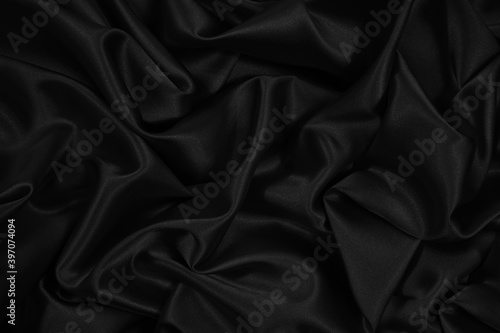 Black silk satin. Black elegant shiny fabric background. Beautiful abstract background.