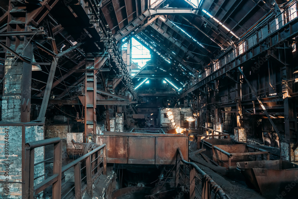 Large hangar or workshop of old rusty industrial metallurgical plant, atmosphere of destruction and post-apocalypse.