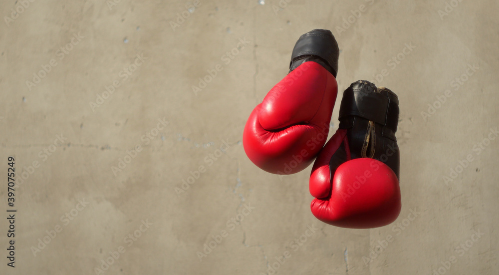 Red boxing gloves hanging against concrete wall. Sport club banner. Copy space. Gym trainings 