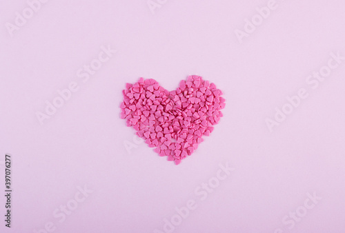 Hundreds of tiny pink heart-shaped hearts lie in the shape of a large heart as a symbol of romantic love