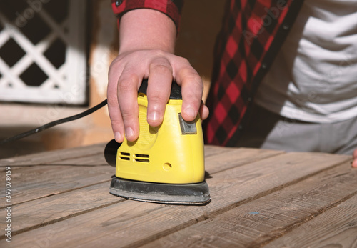 Man with checkered shirt sanding a pallet