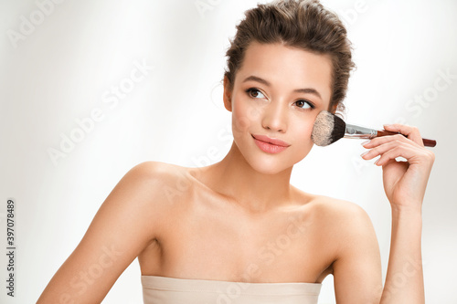 Woman applying powder on the face using makeup brush. Photo of woman with perfect makeup on white background. Beauty concept