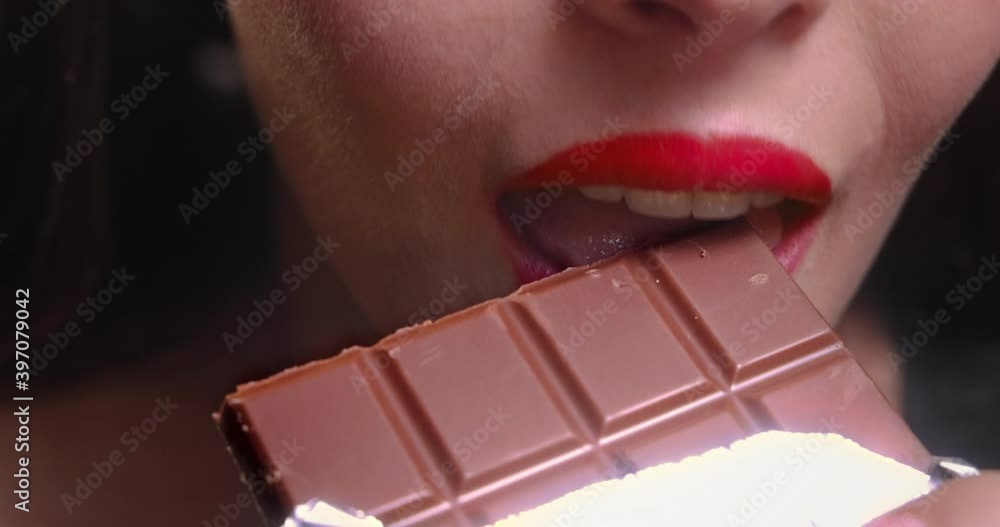 Young woman mouth biting chocolate bar