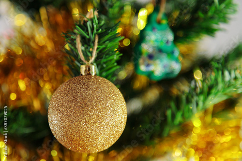 A golden toy hangs on the tree. Tinsel, new year, shine of garlands.
