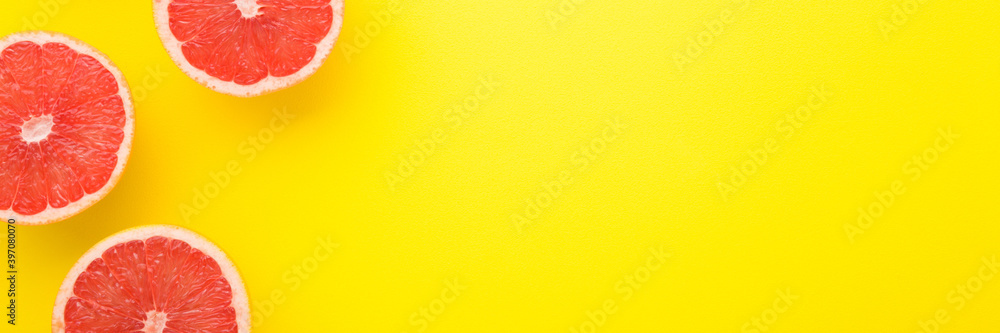 Bright halves of red grapefruits. Wide banner of beautiful fresh fruits. Empty place for text on bright yellow table background. Closeup. Top down view. Bright halves of red grapefruits. Wide banner of beautiful fresh fruits. Empty place for text on bright yellow table background. Closeup. Top down view.