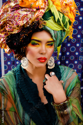 beauty bright woman with creative make up, many shawls on head like cubian, ethno look closeup photo