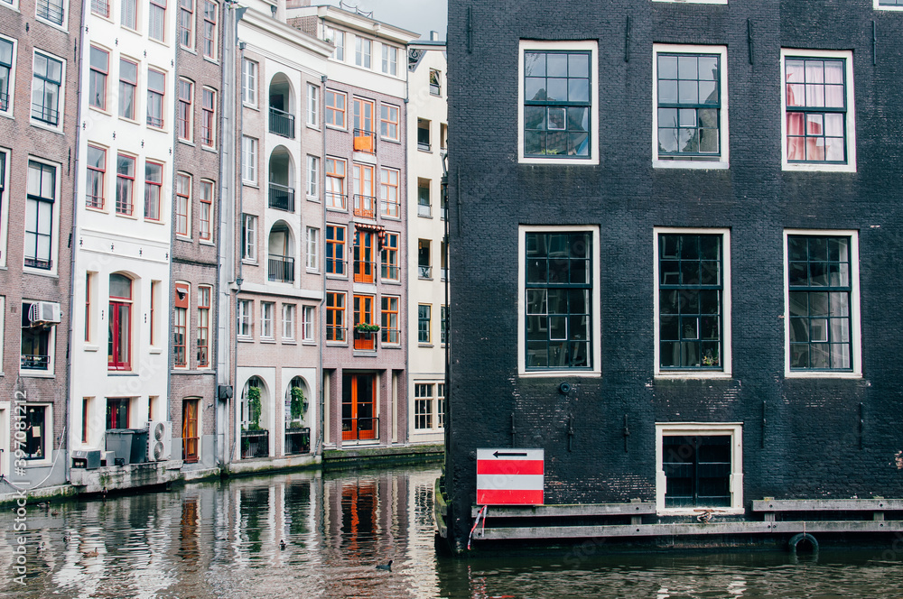 Classic houses located in a canal in Amsterdam The Netherlands iwith a red and white signal with an arrow