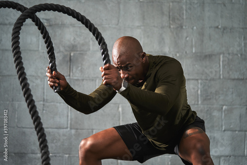 Black man training with battle ropes in crossfit photo