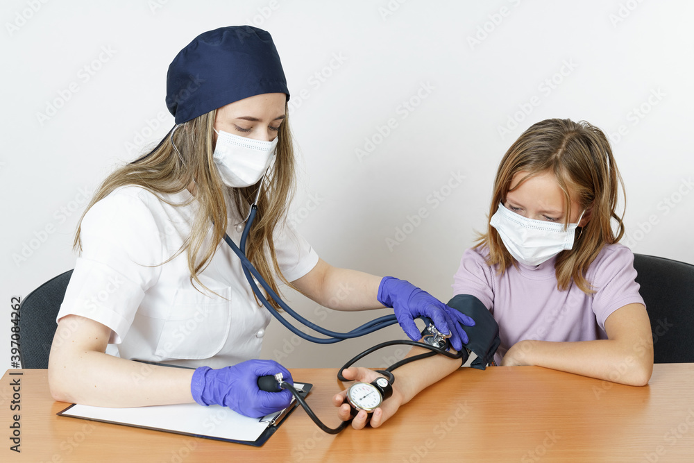 Medicine and health concept. Teenage girl at a pediatrician appointment. The doctor measures the pressure. Medicine and health concept. Teenage girl at a pediatrician appointment. The doctor measures the pressure.