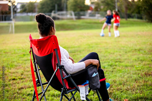 Supportive mom watches daughters play soccer
