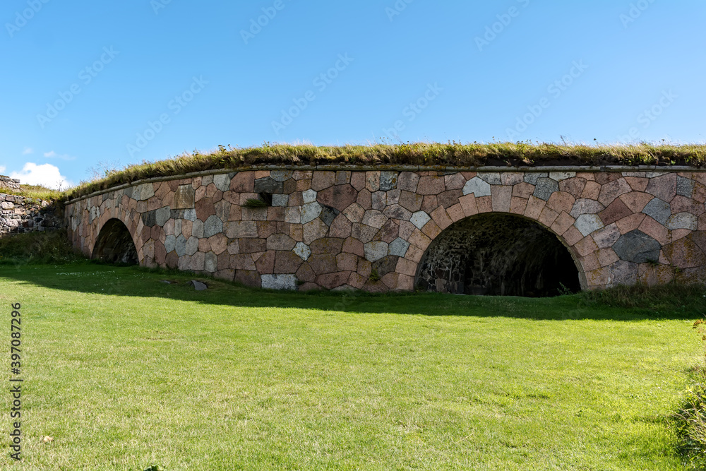 Military architecture of Suomenlinna bastion fortress at Kustaanmiekka island and bright green lawn in front.