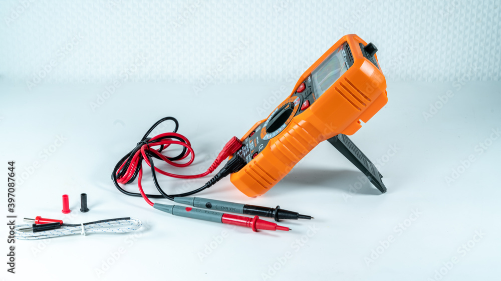 Orange and black multimeter, on white background, object for measuring electricity and temperature