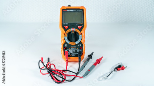 Orange and black multimeter, on white background, object for measuring electricity and temperature