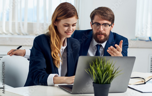 Business man and woman in suit with laptop and flower potted office staff communication