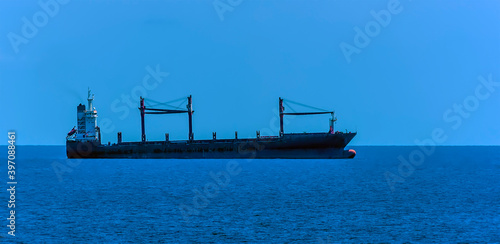 A small cargo ship at sea approaching the Singapore Straits in Asia in summertime