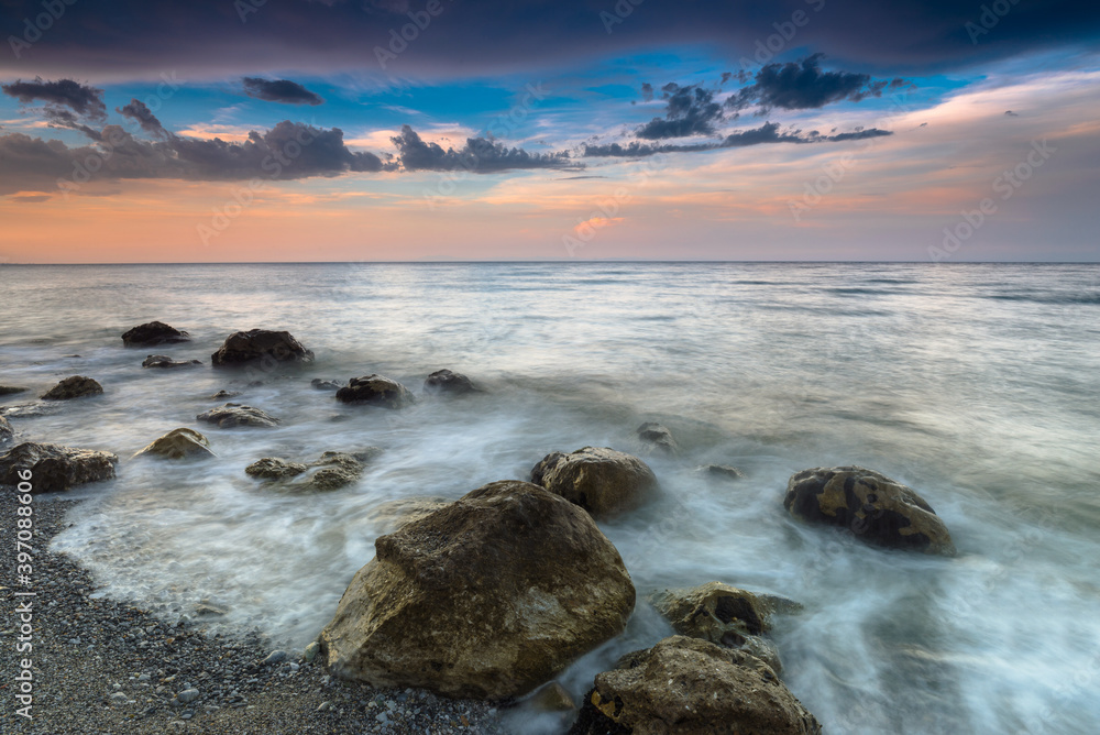 Amazing landscape of sea at sunset. Colorful evening view of the dramatic sky,  waves and rocky sea beach. Long exposure image. Concept of the seascape. Natural background.