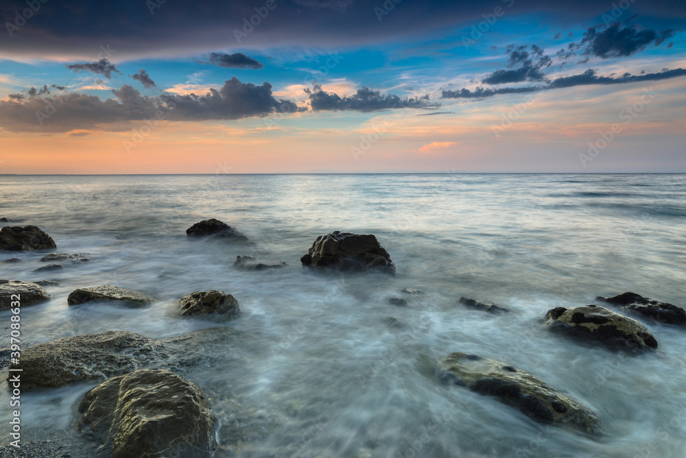 Obraz premium Amazing landscape of sea at sunset. Colorful evening view of the dramatic sky, waves and rocky sea beach. Long exposure image. Concept of the seascape. Natural background.