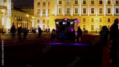 Outdoor view of Tsar horse carriage in front of Winter Palace landmark tourist attraction at eveningtime. Coach on the square and womans in traditional Russian clothes. photo