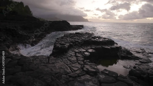 Waves crash on rocky coastline in Kauai, wide