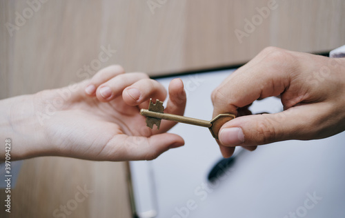 handing the key from hand to hand to the office business finance work documents