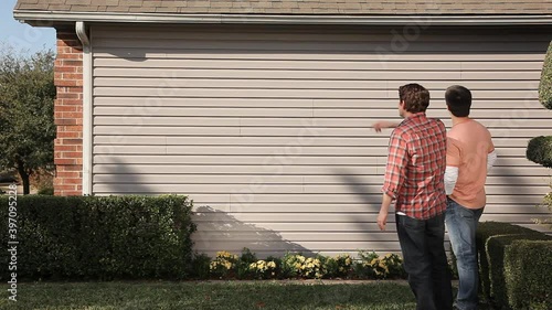 Caucasian men talking at exterior wall of house photo