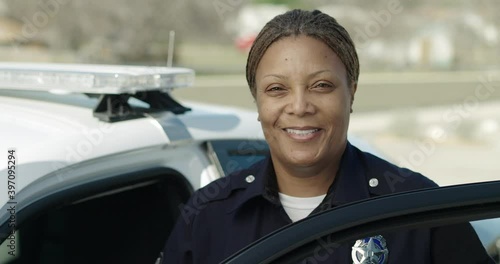 Police officer standing at police car and smiling photo