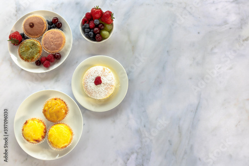 Fotografie A top down view of an assortment of Japanese cheese tarts and a jiggle soft Japanese sponge cheesecake on a white marble worksurface